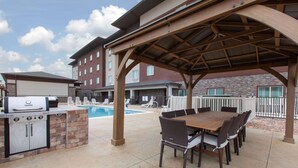 An outdoor patio with a barbecue grill, pool, and dining area. - Hawthorn Extended Stay by Wyndham Odessa (Odessa)