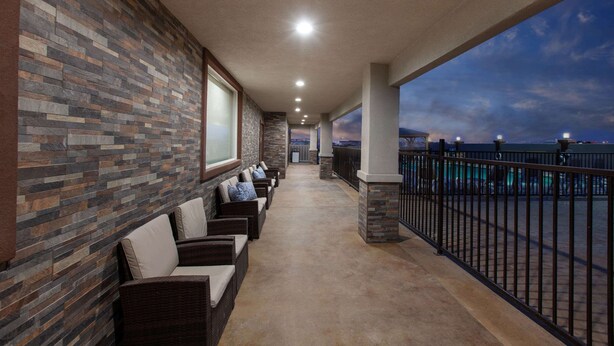 A covered outdoor seating area with stone walls and a view of the pool. - Hawthorn Extended Stay by Wyndham Odessa (Odessa)