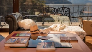 A cozy reading area with a leather sofa, a glass coffee table with books, a hat, and a blanket. - Villa Beluno Hotel & Spa, small luxury hotels of the world (San Carlos de Bariloche)