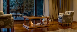 Una sala de estar acogedora con una mesa de centro de madera, dos sillones y vistas a un balcón con mobiliario exterior.