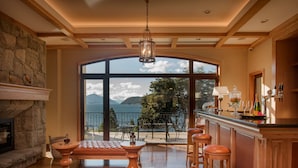 A spacious living area with a fireplace, leather seating, and a view of the outdoors. - Villa Beluno Hotel & Spa, small luxury hotels of the world (San Carlos de Bariloche)