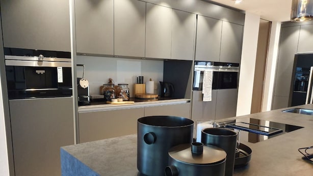 Een moderne keuken met ingebouwde apparatuur, een groot eiland met zwarte pannen en een strak design.