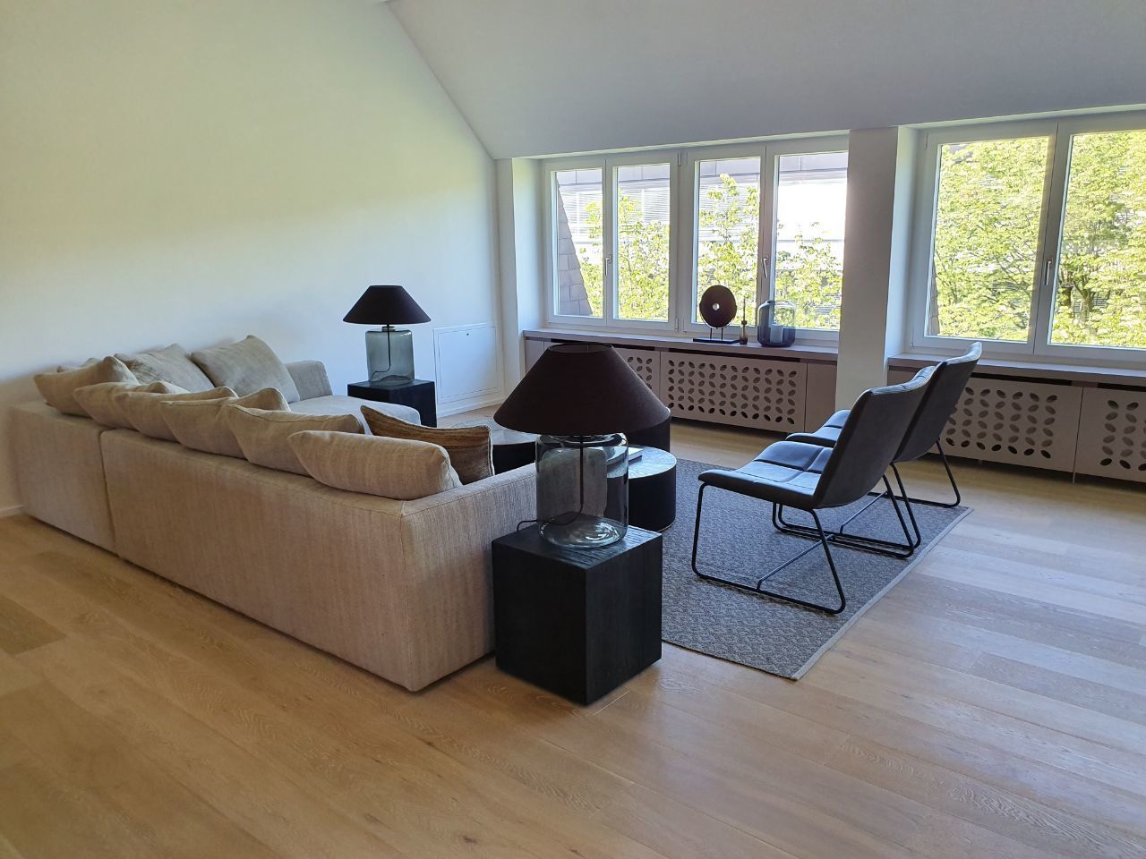 A modern living room with a sofa, two side tables, and a chair.