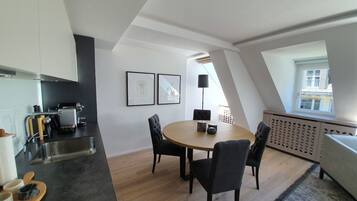 Eine moderne Küche mit Essbereich, ausgestattet mit einem runden Tisch und Stühlen, einer schwarzen Arbeitsplatte und einem Fenster für natürliches Licht.