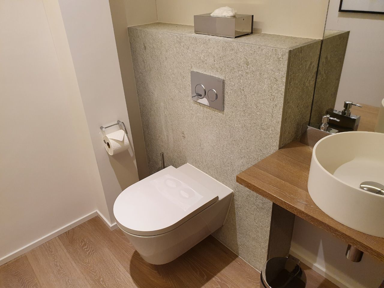 A small bathroom with a toilet, a sink, and a mirror.