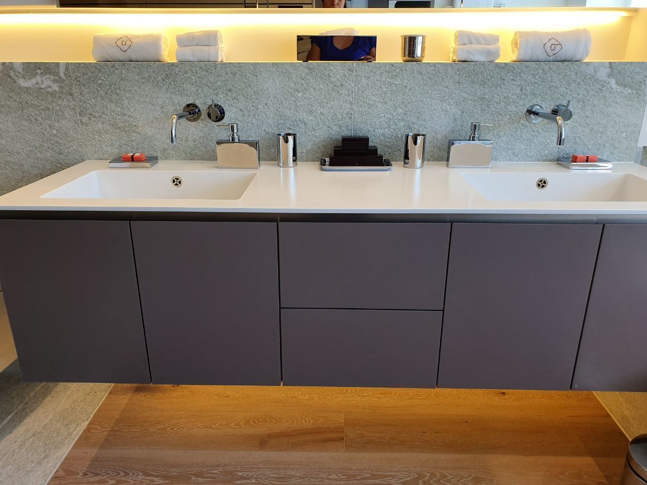Une salle de bain moderne avec deux lavabos, un miroir et un porte-serviettes.