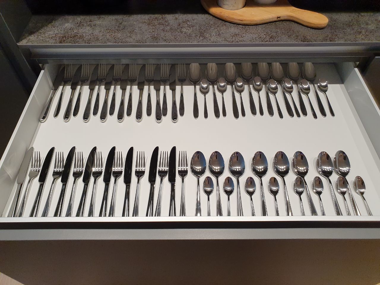 A drawer containing an organized set of silverware, including forks, knives, and spoons.
