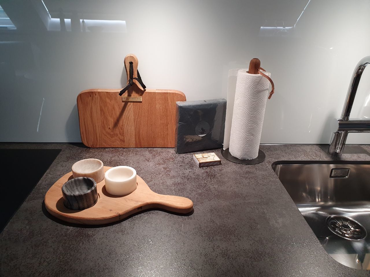 Une cuisine équipée d’une planche à découper en bois, de bols, d’un rouleau d’essuie-tout et d’un évier.