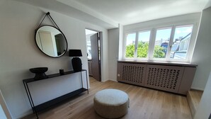 Een moderne kamer met een rond poef, een console tafel met spiegel, en een radiator.
