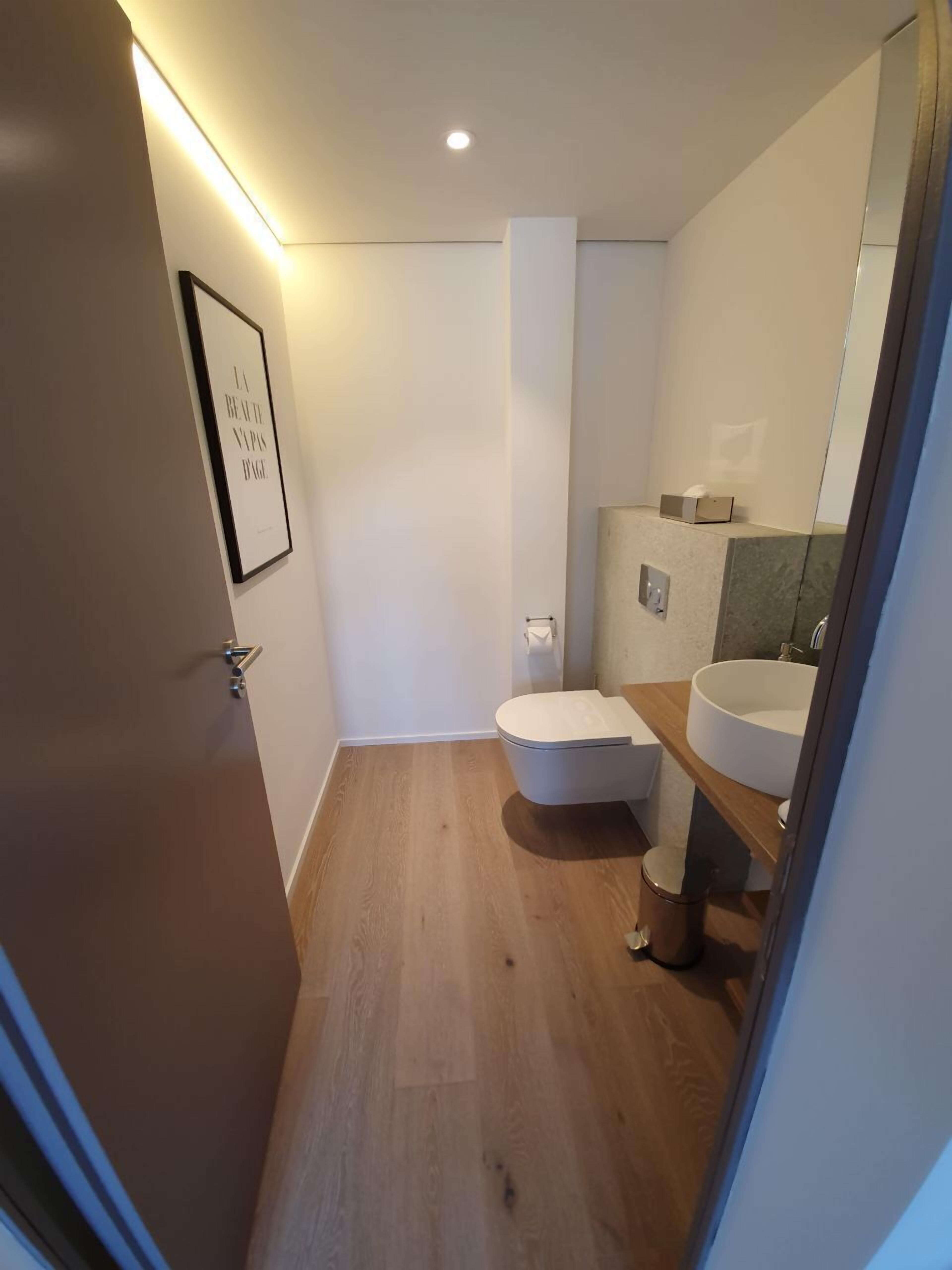 Ett modernt badrum med toalett, handfat och ett inramat citat på väggen.