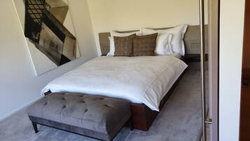 A bedroom with a bed, a bench, and a large abstract painting on the wall.