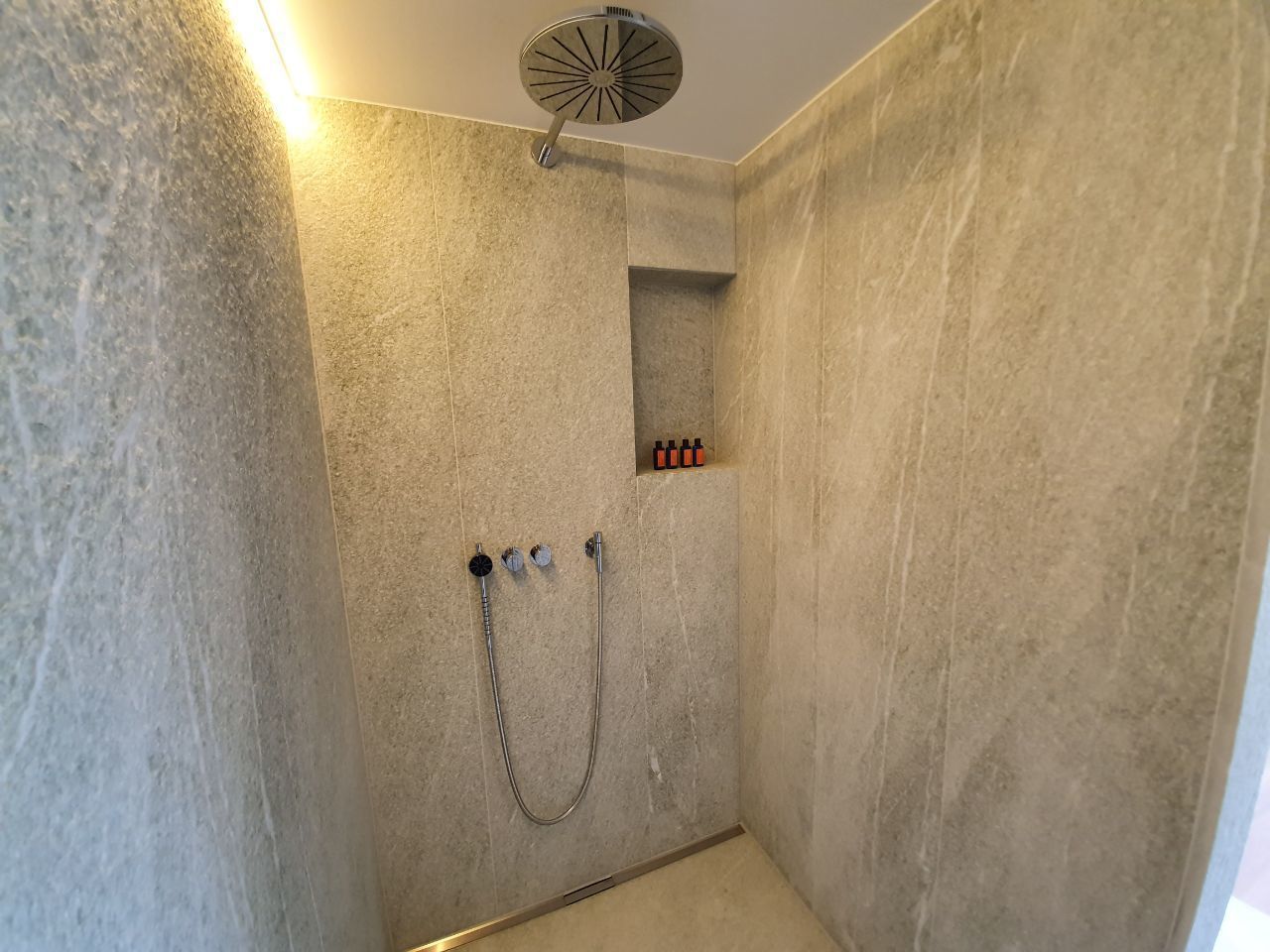 Une douche équipée d’un pommeau de douche à main et d’un panneau de commande fixé au mur.