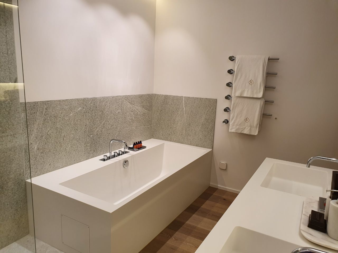 A modern bathroom with a freestanding bathtub, a separate sink, and a towel rack with multiple towels.