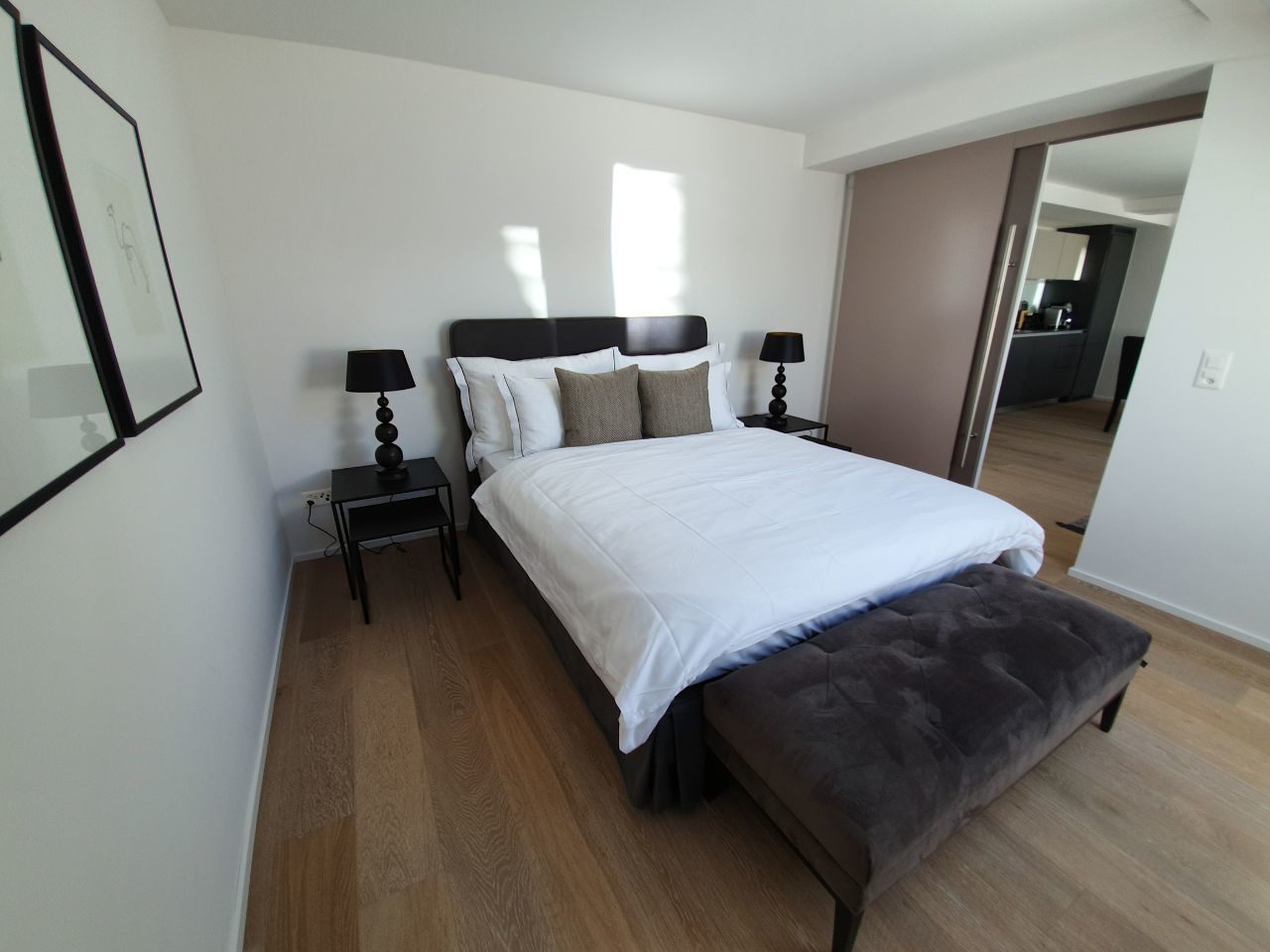 A bedroom with a bed, two bedside tables, a bench, and a mirror.