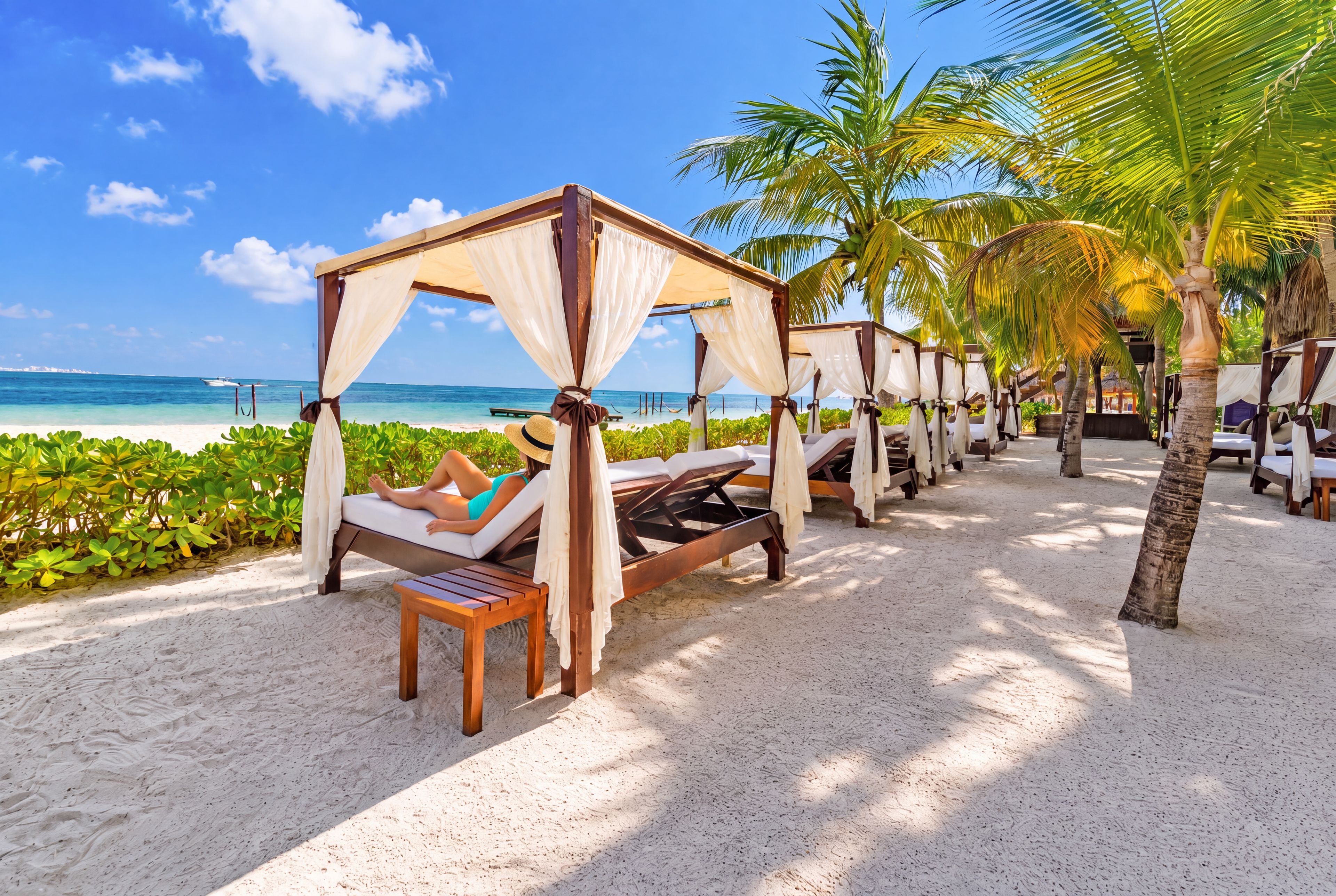 A beachside resort with overwater bungalows, clear blue skies, and a calm sea.