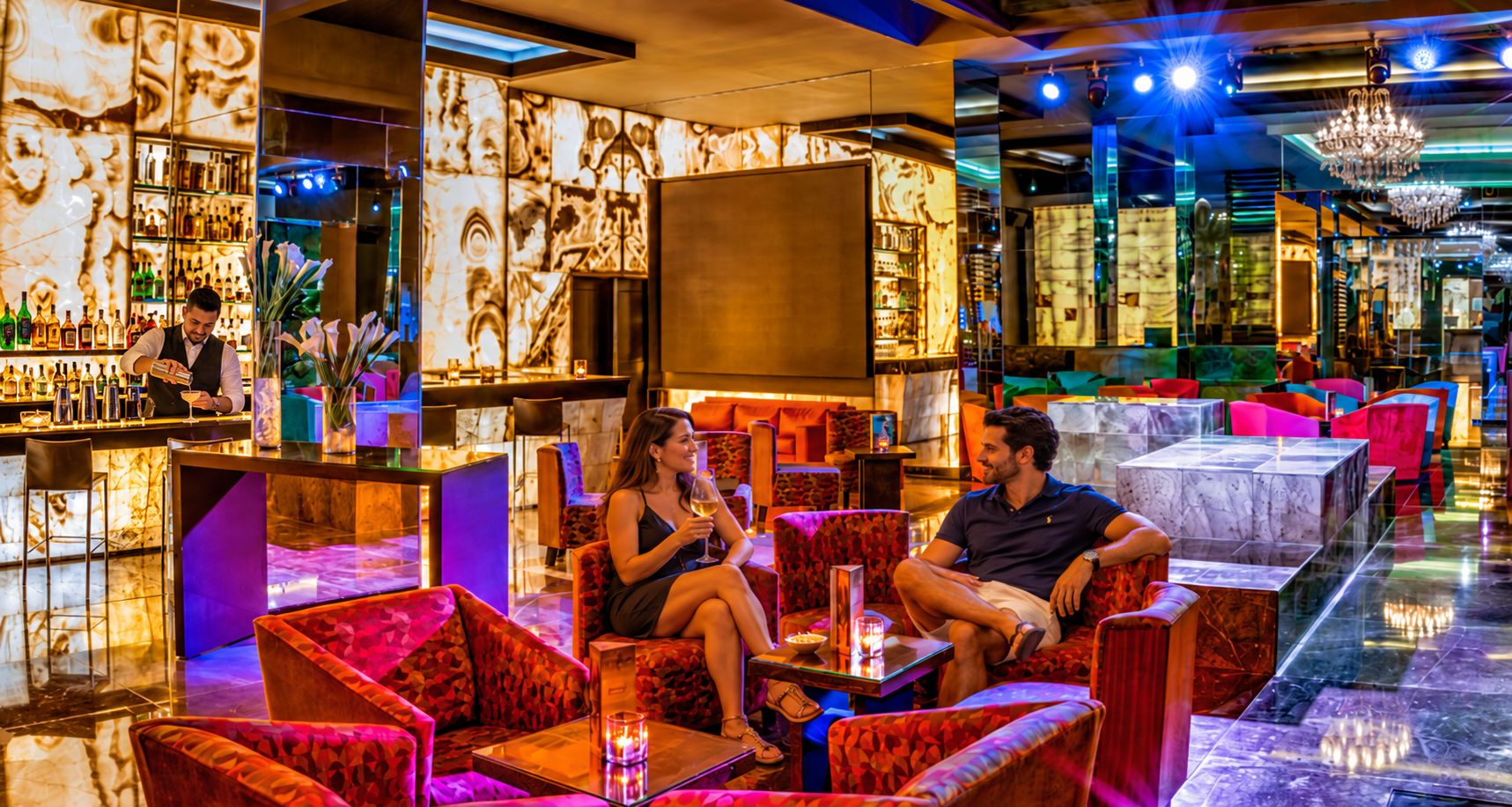Een bar met zitplaatsen, een televisie en diverse flessen.