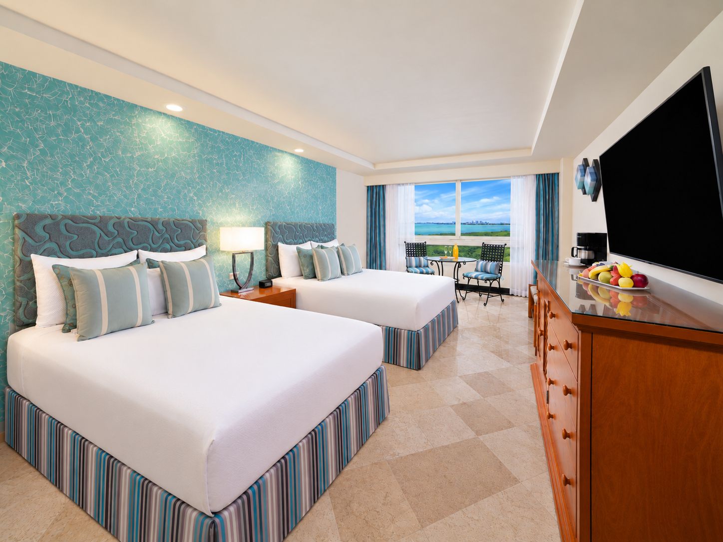 Une chambre d’hôtel avec deux lits, une télévision, un coin repas avec vue et un balcon.