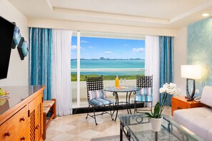 A hotel room with a balcony, a dining table, chairs, a sofa, a TV, and a lamp. - The Sens Cancun By Oasis (Cancun)