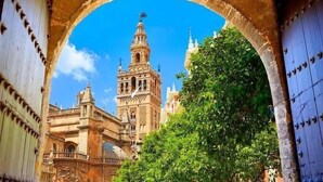 A historic building with a prominent tower and arches, viewed through a doorway. - Hub Hostel Seville (Seville)