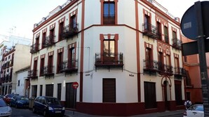 A multi-story building with balconies, a sign reading "COLLES," and a "BANHO" sign indicating a nearby public bath. - Hub Hostel Seville (Seville)