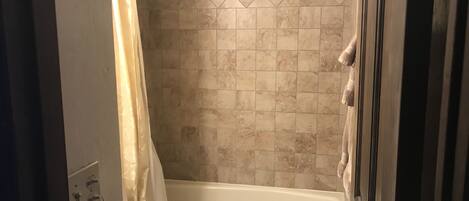 A bathroom with a bathtub, toilet, and shower curtain.
