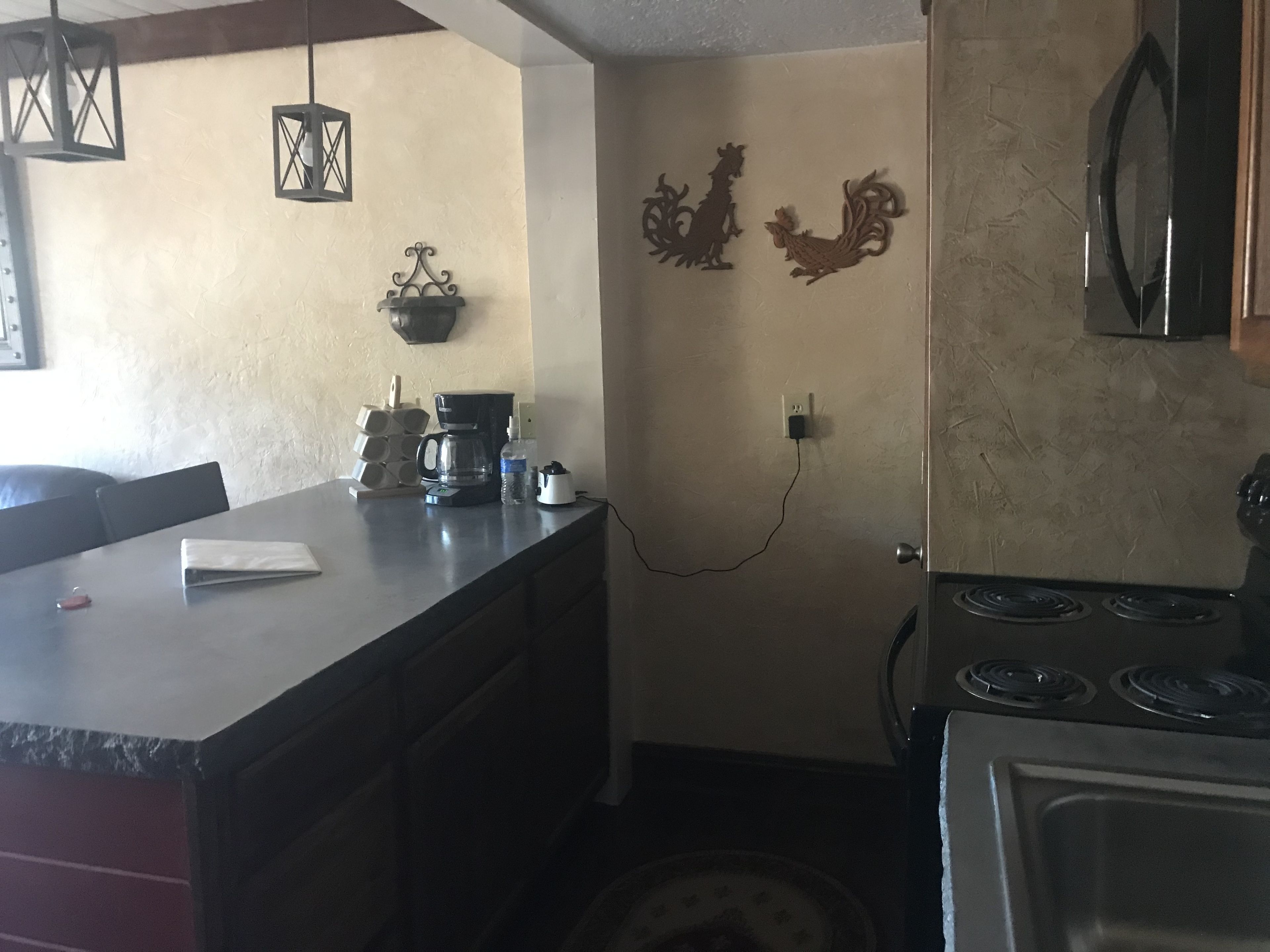 A kitchen with a stove, a coffee maker, and wall decorations.