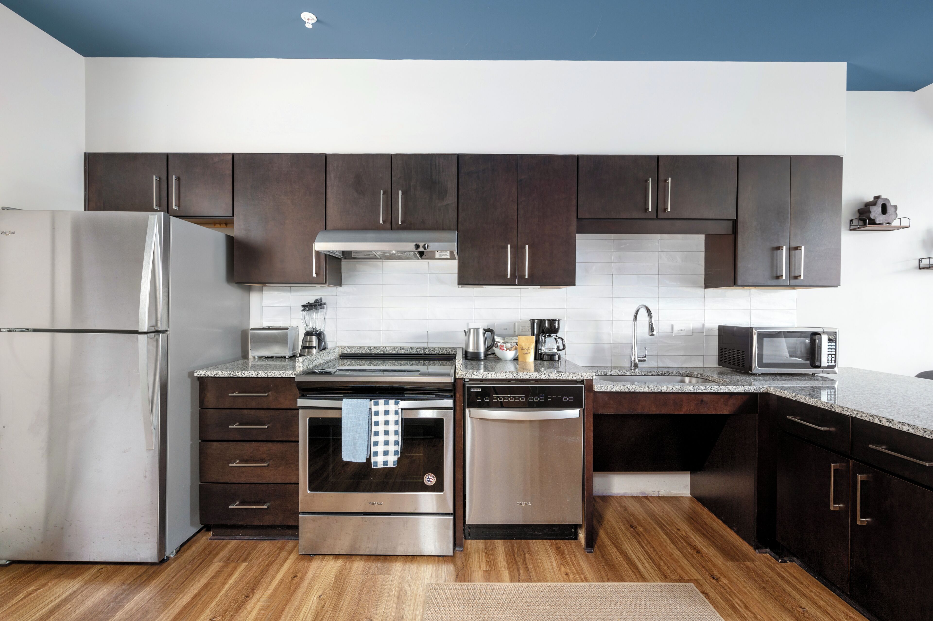 A modern kitchen with dark cabinets, stainless steel appliances, and a granite countertop.