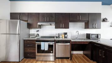 Una cocina moderna con gabinetes oscuros, electrodomésticos de acero inoxidable y encimera de granito.