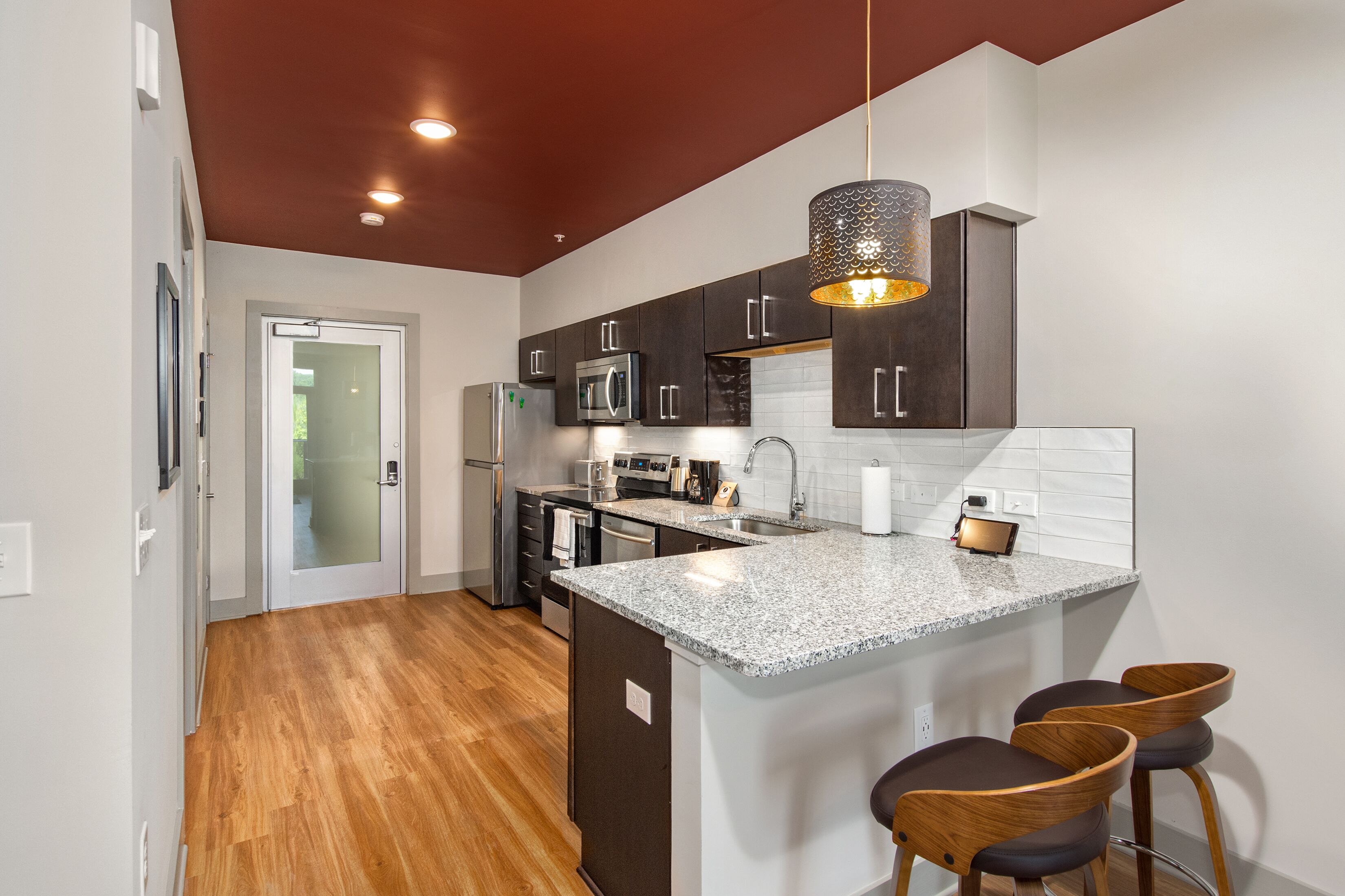 A modern kitchen with dark cabinets, granite countertops, and a central island with bar stools.
