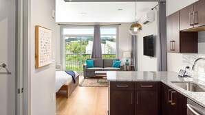 A modern kitchen with dark cabinets, a granite countertop, and a stainless steel sink. - River Row Flats (Asheville)