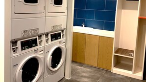 A laundry room with stacked washing machines, a blue tiled wall, and a wooden cabinet. - Holiday Inn Express Shanghai Jiading New City by IHG (Shanghai)