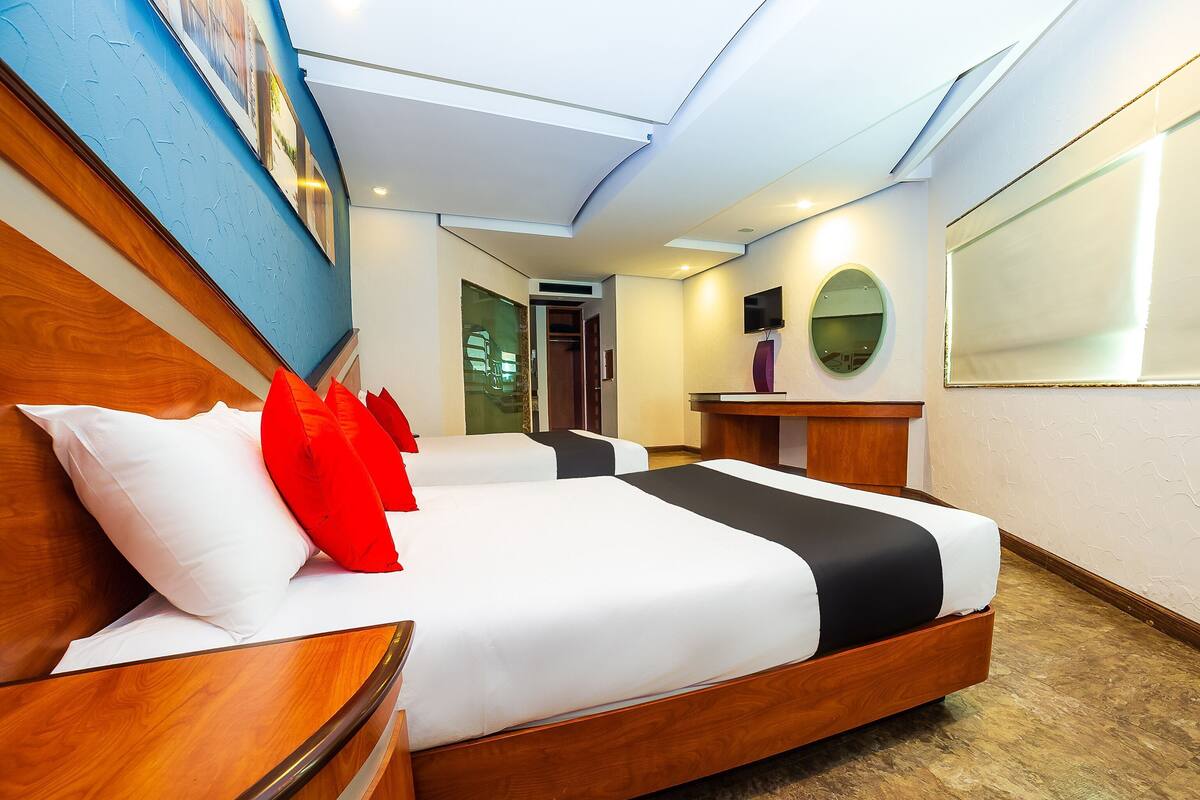 A hotel room with a large bed, a wooden headboard, a desk, and a mirror.