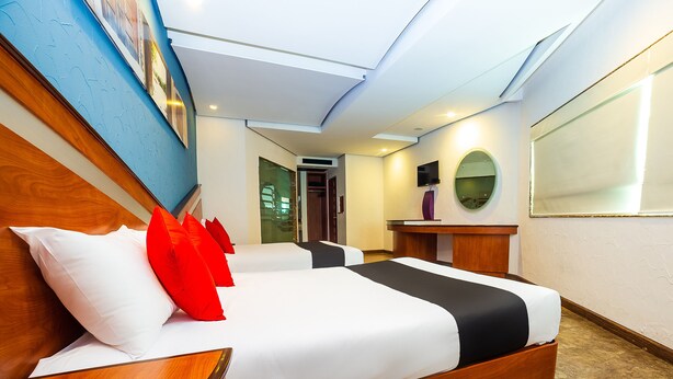 A hotel room with a large bed, wooden headboard, and a desk with a mirror. - Hotel Verona (Tlalnepantla de Baz)
