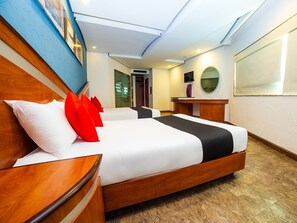 Habitación de hotel con una cama grande, cabecera de madera y un escritorio con espejo.
