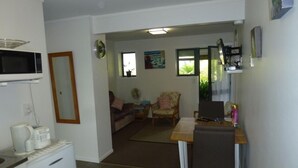 A compact living space with a kitchenette, a dining area, and a seating area with a sofa and chairs. - Monty's self-contained unit (Kawhia)