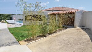Uma propriedade residencial com piscina, jardim com diversas plantas e casa com telhado de telhas vermelhas.