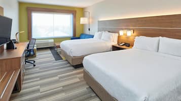 Quarto de hotel com duas camas, uma mesa, uma cadeira, uma televisão e janela com vista.