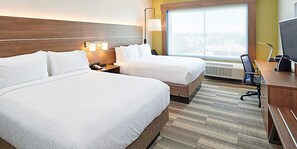 A hotel room with two beds, a desk, a chair, a lamp, and a large window.