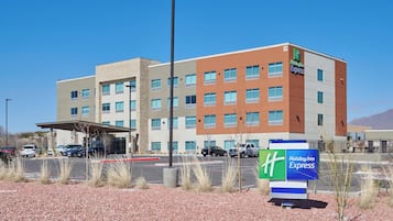 Et Holiday Inn Express hotel med moderne design, flere etager og en parkeringsplads foran.