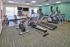 Een fitnessruimte met loopbanden, elliptische trainers en krachtapparaten.