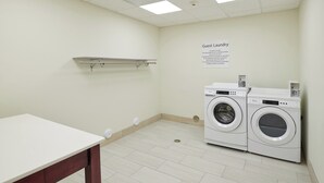 Un lavadero con dos lavadoras Whirlpool, una mesa blanca y un letrero que indica que es solo para huéspedes.