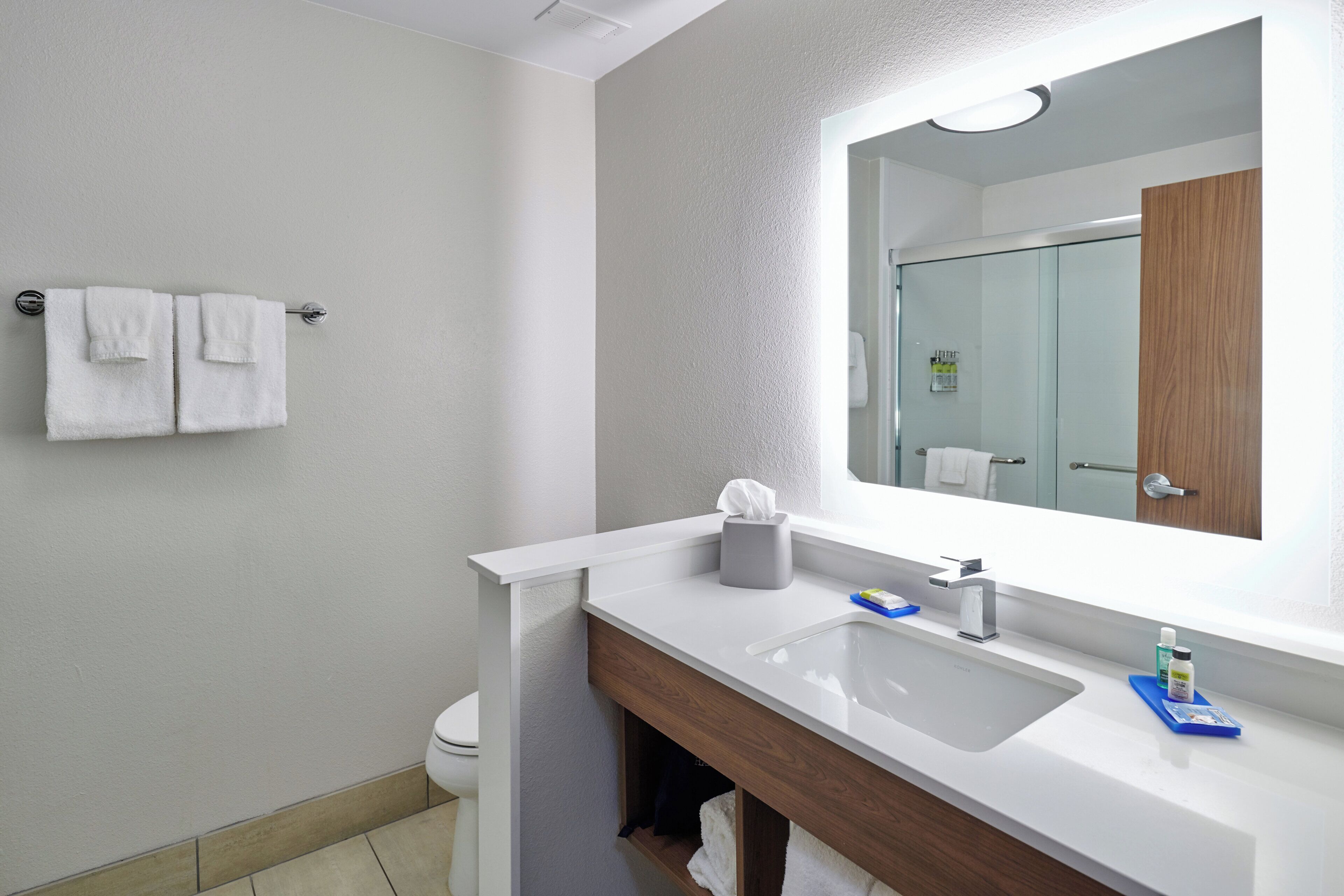 Een moderne badkamer met een witte wastafel, een spiegel en een handdoekrek.