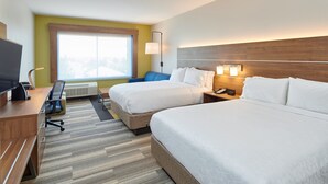 Quarto de hotel com duas camas, uma escrivaninha, uma cadeira, uma TV e uma janela com vista.