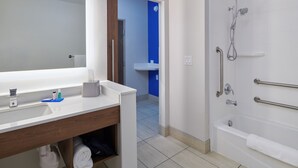 Casa de banho com lavatório branco, espelho e zona de duche.