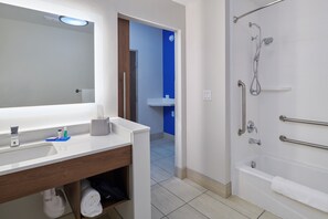 A bathroom with a white sink, mirror, and shower area.