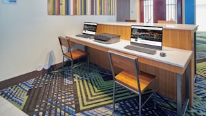 Centro de negocios con dos estaciones de computadoras, sillas y alfombra estampada.