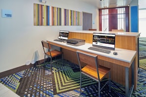 Centro de negocios con dos estaciones de computadoras, sillas y alfombra estampada.