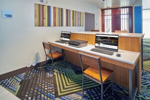 Centro de negocios con dos estaciones de computadoras, sillas y alfombra estampada.