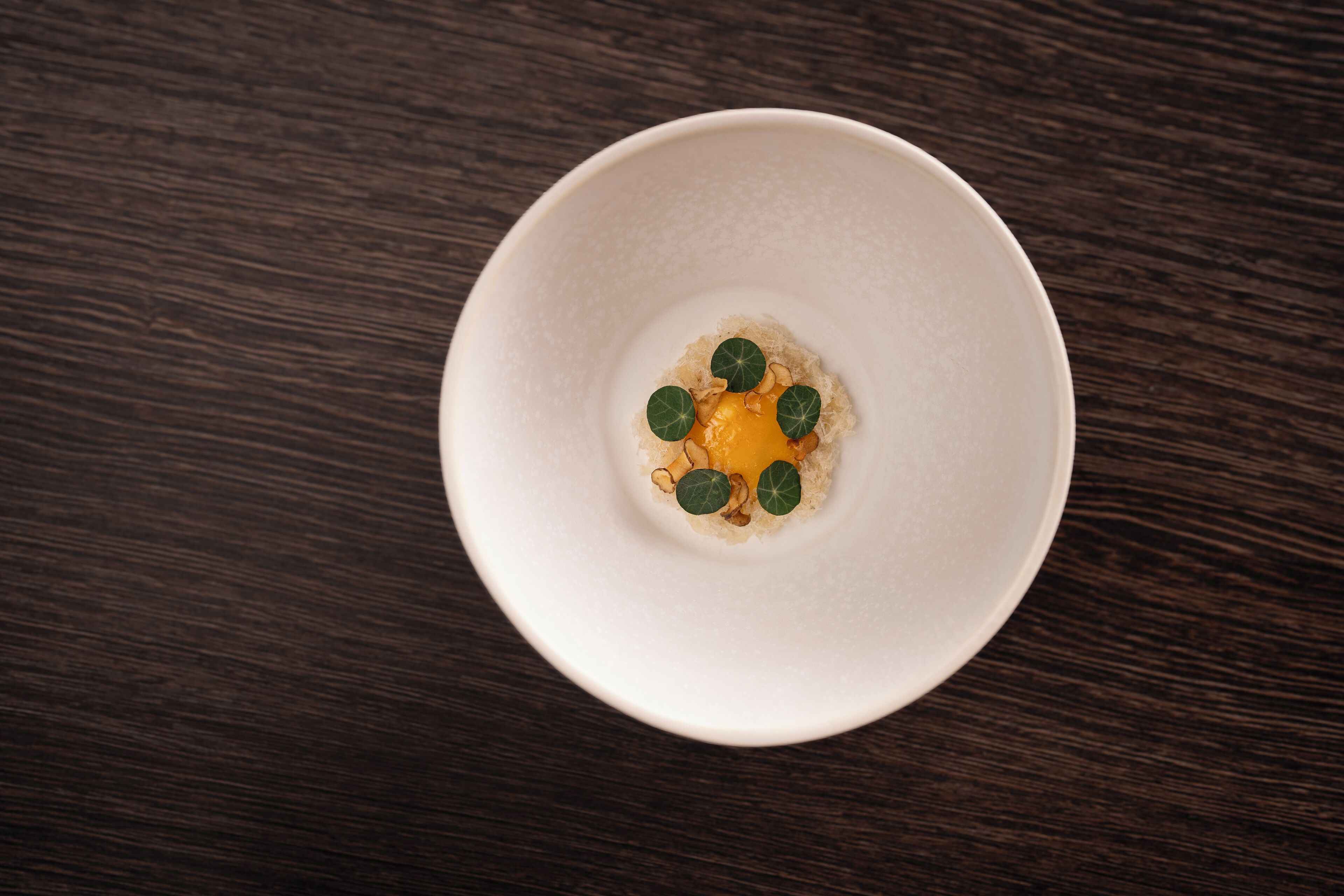 A white bowl on a dark wooden table.