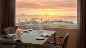 A table set for dining with a candle, glasses, and a bottle, overlooking a sunset view. - Hotel Arctic (Ilulissat)